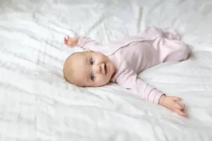 happy baby laying on a bed looking at the camera